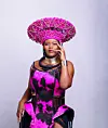 Rapper Awakhiwe wearing a dramatic pink beaded headpiece and magenta-black outfit in a studio portrait.