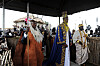King Oyo in blue ceremonial robes stands among attendants at a traditional coronation ceremony in Uganda.