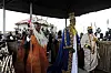 King Oyo in blue ceremonial robes stands among attendants at a traditional coronation ceremony in Uganda.