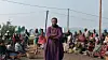 Clémentine U. Nyirinkindi as Veneranda stands with her arms crossed in front of a large seated crowd in a still from the Rwandan film Ben’Imana.