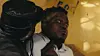 A frightened man in a light blue shirt is held at gunpoint by another man wearing a black leather hat in a still from the Ugandan-Canadian thriller Last Taxi to Kawempe.