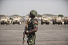 Nigerian soldier with a rifle stands before armored vehicles on a parade ground in Lagos.