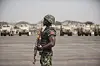 Nigerian soldier with a rifle stands before armored vehicles on a parade ground in Lagos.