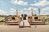 An elephant stands behind a wooden deck with outdoor furniture in a safari.
