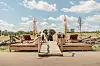An elephant stands behind a wooden deck with outdoor furniture in a safari.