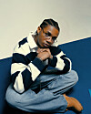 A photo of KiDi wearing a striped shirt, light blue denim jeans and brown timberland shoots.