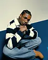 A photo of KiDi wearing a striped shirt, light blue denim jeans and brown timberland shoots.