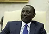 Kenyan President William Ruto sits in a cream-colored chair during a White House meeting.