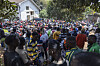 A dense crowd gathers outside a tree-lined embassy compound in Nairobi, with people wearing colorful clothing.