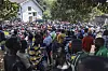 A dense crowd gathers outside a tree-lined embassy compound in Nairobi, with people wearing colorful clothing.