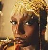 Close-up portrait of a person wearing a gold headpiece and holding a golden accessory near their lips.