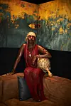 Woman in red seated on a brown sofa beneath a textured abstract painting.