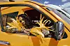 Passenger leaning from a decorated orange vehicle window with gold floral ornaments.