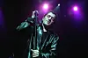 Rachid Taha sings into a microphone under purple lights at Royal Festival Hall.