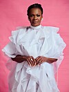 Judith Sephuma in a voluminous white ruffled dress posing against a pink background.