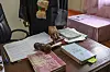 A magistrate’s hand rests near a wooden gavel, case files and legal books on an office desk.