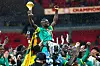 Senegal players raise the Africa Cup of Nations trophy amid confetti and cheering supporters.