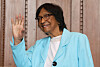 Navi Pillay smiles and waves while wearing glasses and a turquoise blazer.
