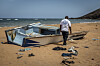 An IOM worker examines a damaged boat on a sandy beach near Obock, Djibouti.