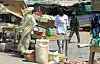 Vendor stands beside sacks and produce at a busy open-air market in Abyei.