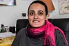 Portrait of Lina Attalah seated indoors in Cairo, wearing a magenta scarf and dark sweater.