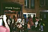A group of young people outside London\u2019s Arcola theater at night, laughing and smiling at the camera.