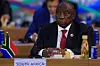 Cyril Ramaphosa sits at a desk labeled South Africa.