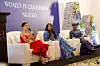 A photo of Meghan Markle speaking on stage with Dr Ngozi Okonjo Iweala and Mo Abudu beside her.