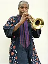 Femi Kuti stands while played a trumpet.