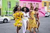 \u2018The Smart Money Woman\u2019 stars Kemi Lala Akindoju, Ini Dima-Okojie, Osas Ighodaro, Toni Tones holding hands and laughing as they cross the road in a street with colorful buildings.