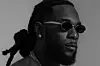 Burna Boy poses for a black and white press image wearing sunglasses.