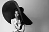 Adelle Onyango poses for a photo wearing a giant wide-brimmed hat.