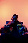 Mr Eazi sits in neon lighting.