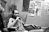 A black-and-white photo of Fela Kuti sitting pensively in an armchair in his compound, Lagos, Nigeria, circa 1983