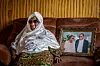 Mariam Doumbia sits in mourning on a sofa at her home next to a photo of her and Amadou together.