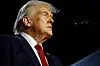 A close-up shot of former U.S. president Donald Trump in a deep blue suit, white shirt, and red tire.