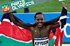 A photo of Faith Kipyegon holding the Kenyan national flag and smiling.