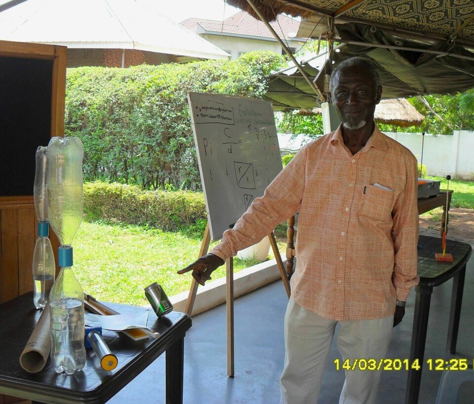 Jacob and his wife Jane Ashong opened the Ghana Planetarium in 2009 An image of a man in an orange shirt, Jacob Ashong, pointing to a tilted can on a table.