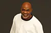 Richard Mofe-Damijo in an all-white outfit, posing for a photo with a smile and one hand in his pocket.