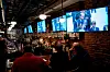 An image of people in a pub watching the state funeral of Queen Elizabeth II on TV screens.