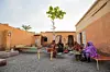 A group of women wearing toubs and two young children are sitting in a hosh, a Sudanese yard.