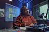 A still from \u2018Big Girl, Small World,\u2019 showing star June Njenga in a studio talking into a microphone.