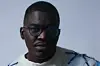 Opeyemi Ademola in a white sweater and glasses.