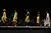 An image of five models walking the catwalk, dressed in yellow outfits
