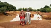 An image from the film Bravo, Burkina! of a man and a woman kneeling at a small lake.