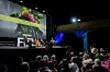 A panel of four people, two men, and two women, are sitting on a stage in a cinema, facing an audience. The festival's flower ban is projected on the screen behind them.