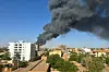 ​A column of smoke rises behind buildings near the airport area in Khartoum on April 19, 2023, amid fighting between the army and paramilitaries following the collapse of a 24-hour truce.