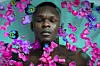 An image of Israel Adesanya floating in a pool of flowers.