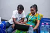 An image of two people sitting down looking at a laptop. For its first event in Ghana, Afrocuration partnered with nonprofit independent internet radio station, Oroko Radio, and the Twi User Language Group.