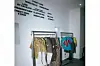 Two metal clothing racks display a curated collection of colorful and patterned streetwear pieces under a wall featuring brand names like \u201cStreet Souk,\u201d \u201cSnug World,\u201d and \u201cWande Esan.\u201d